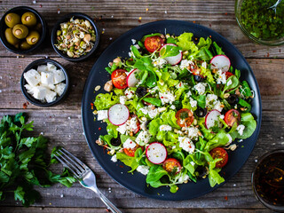 Fresh Greek salad - feta cheese, cherry tomatoes, lettuce and onion wooden table
