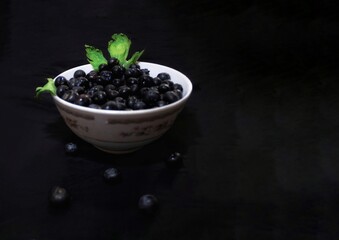 Arándanos con menta en un plato blanco con fondo negro 