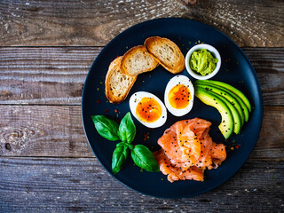 Salmon salad - smoked salmon boiled egg and vegetables on wooden background
