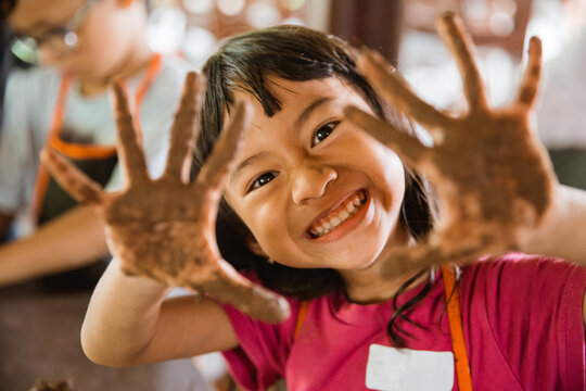 happy little girl showed her dirty hands from playing clay with her friends
