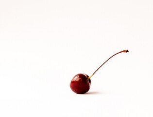 A single ripe cherry on a light background with space for text.