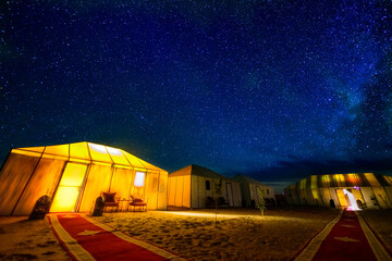 A sky full of staras and milky way above a desert camp in Sahara desert in Morocco.  - obrazy, fototapety, plakaty
