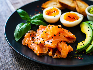 Salmon salad - smoked salmon boiled egg and vegetables on wooden background
