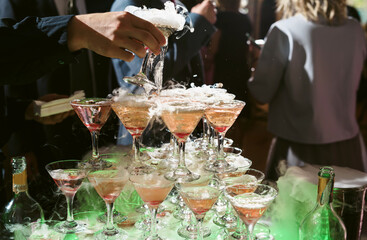 Champagne slide. Pyramid or fountain made of champagne glasses with cherry and steam from dry ice