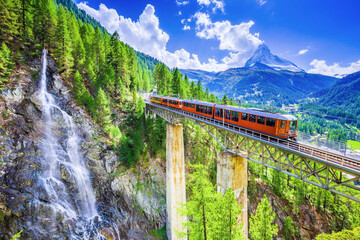 Zermatt, Switzerland. Gornergrat tourist train with waterfall, bridge and Matterhorn. Valais region. - obrazy, fototapety, plakaty