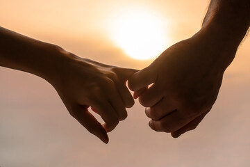 a couple hold each other's hands in the background of the sunset