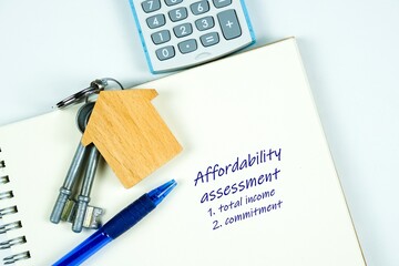 Conceptual image of debt service ratio for home loan repayment appraisal. Wooden key chain calculator notepad and pen in visibility. Focus on keychain.