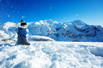 Fototapeta na wymiar Side portrait of a teenage girl throw snow in the air over mountain peaks on background