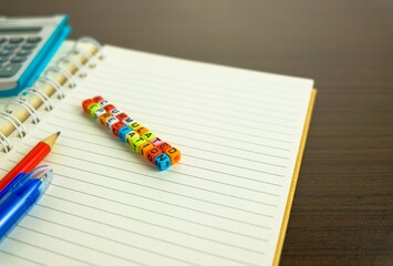 Conceptual of accumulated depreciation in financial statements. Colorful alphabet beads stacked forming the words over dark table. Spiral notebook and pencil visible. Focus on text on beads at front.