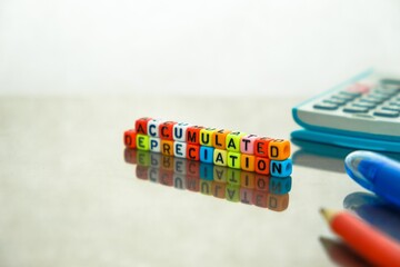Conceptual of accumulated depreciation in financial statements. Colorful alphabet beads stacked forming the words over dark table. Spiral notebook and pencil visible. Focus on text on beads at front.