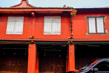 Image of red painted pre-war shophouse building situated along a road called merdeka road leading to unesco heritage site Malacca city Malaysia. Selective focus.