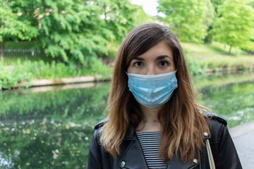 Attractive young woman going for a walk throug Regent´s canal while wearing a face mask  during coronavirus outbreak