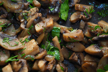 Fried champignon with herbs in a pan.