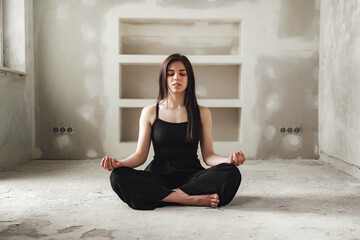 cross legged young woman meditate in empty room