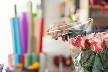 The work of the florist. Flower packaging. Creating a flower bouquet. Roses in a package. Selective focus.