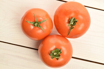 Fresh ripe, juicy, organic tomato, close-up, on a white painted, wooden table.