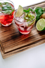 Raspberry cocktail, lemonade with lime, kiwi, mint and pieces of ice on a wooden board. Close-up.