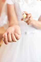 The bride puts the perfume on her hands. Bottle