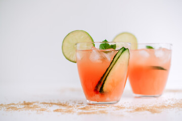 Grapefruit cocktail, lemonade with lime, mint and pieces of ice on a white table with cane sugar.