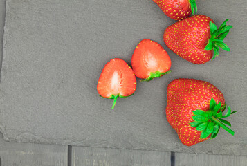 Fresh and sweet strawberries laid out on a table on a dark background