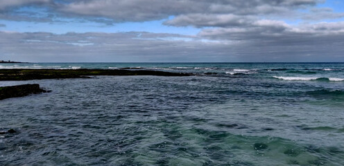 Cobalt blue sea hitting ancient volcanic rocks on Hyeopjae beach