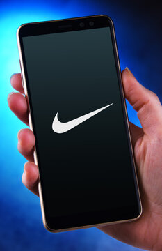 Hand holding smartphone displaying logo of Nike
