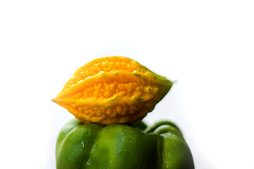 yellow bitter gourd between green capsicum with isolated background, odd one out
