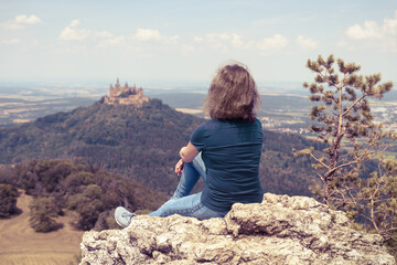 Woman on cliff near Hohenzollern Castle, Germany. This famous castle is landmark of...