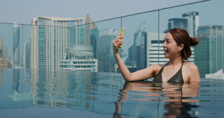 Woman take selfie on cellphone in swimming pool