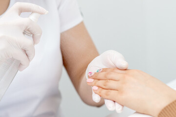 Manicurist is applying spray on client hand. Manicure disinfection with spray.