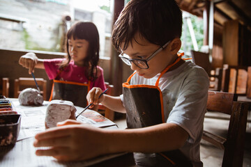 children coloring clay handicrafts with brushes and paint in the pottery workshop gallery