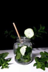 Fresh drink water with mint and cucumber on black background.
