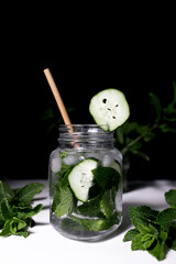 Fresh drink water with mint and cucumber on black background
