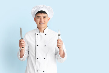 Handsome Asian chef on color background