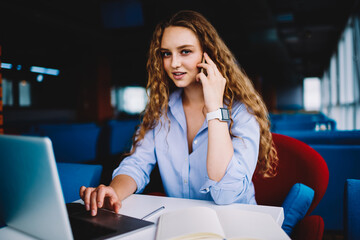 Skilled copywriter having mobile conversation while remotely working in cafe