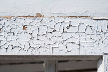 An old wooden window frame with white paint that had already deteriorated in the sun cracked. The...