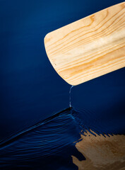 Water dropping from a wooden canoe paddle