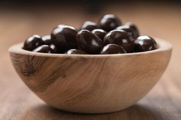 Chocolate drage with almond nuts in olive wood bowl