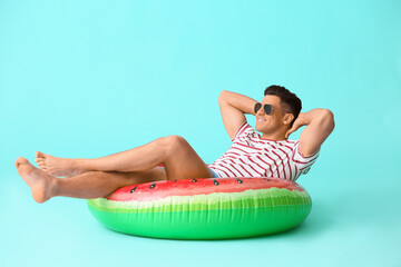 Young man with inflatable ring on color background