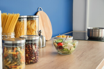 Bowl with salad and products on counter in modern kitchen
