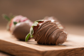 Chocolate covered fresh strawberry on wood background