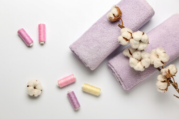 Cotton flowers, threads and soft towels on white background