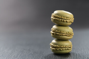 Pistachio macarons stacked on slate board with copy space
