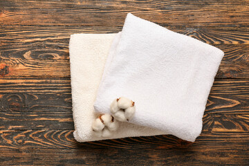 Cotton flowers and soft towels on wooden background