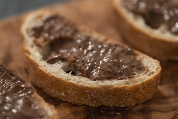Ciabatta slices with chocolate spread on olive wood board