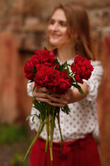 red peonies in the hands of a washed happy girl