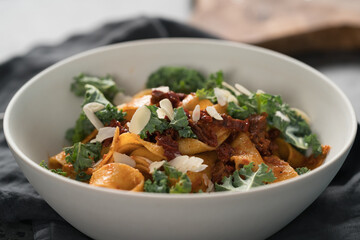 fettuccine pasta with sun-dried tomatoes, almond flakes and kale leaves