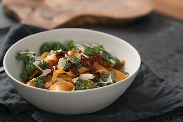 fettuccine pasta with sun-dried tomatoes, almond flakes and kale leaves