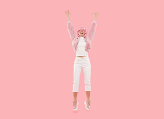 Full length photo of young active female jumping and laughing, isolated on pink background