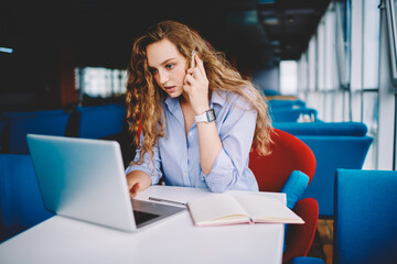 Skilled copywriter having mobile conversation while remotely working in cafe